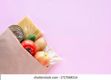 Vegetables, Fruits And Various Grocery Items In Paper Bag On Pink Background. Healthy Food, Delivery, Donation Concept. Top View, Copy Space.