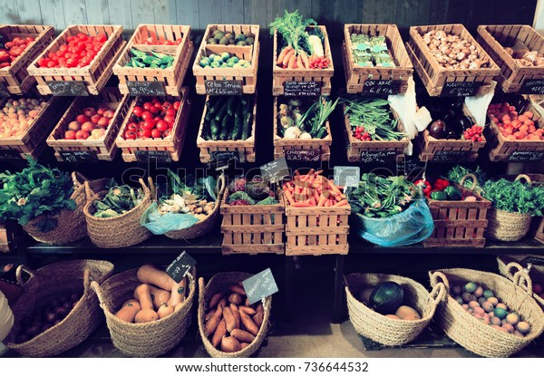 vegetables and fruits in\
wicker baskets on counter of greengrocery. on labels of product\
names in Catalan