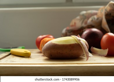  vegetables on a cutting board. close-up of peeled potatoes and in the background potatoes, carrots, red onions. The knife lies nearby.