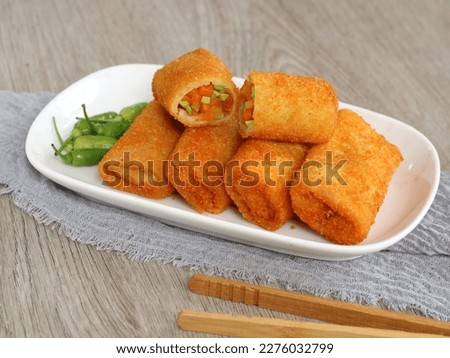 vegetables risoles or risol sayur or risoles sayur stuffed with veggies and enclosed in crepe-like wrappers and rolled into bread crumbs and fried. served on white plate and chili. selected focus 