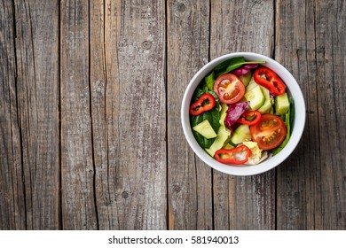Vegetables salad in white bowl on an old wooden table