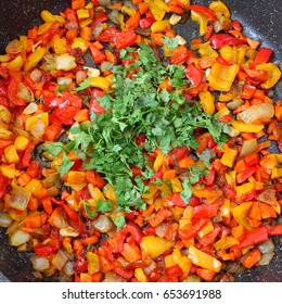 Vegetables stewed. Sweet colored peppers, onion, carrot and red tomato flavored with parsley green leaves serving in a frying pan.  Top view. Vegetarian food background - Shutterstock ID 653691988