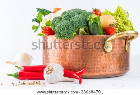 Vegetables for stock ingredients in copper pot on white wooden background copy space.Healthy cooking, dieting, vegetables ingredients for soup or broth.