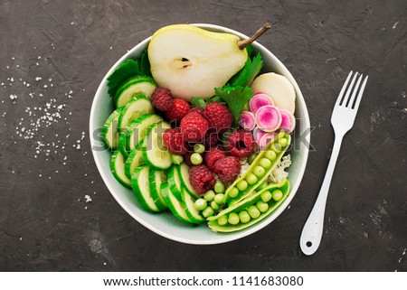 Vegetables summer fruit detox bowl. Vegetarian healthy food. Salads, lettuce leaves, raspberries, green peas, cucumber, carrots, daikon, edible flowers Top View