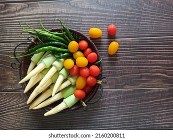 Vegetables. Various Vegetables. Close and Selective Focus on fresh vegetables in the basket. Isolated on wooden table background. There are; Red and yellow Cherry Tomatoes, baby corn and Green Chili. - Powered by Shutterstock