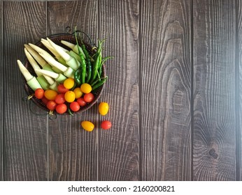 Vegetables. Various Vegetables. Close and Selective Focus on fresh vegetables in the basket. Isolated on wooden table background. There are; Red and yellow Cherry Tomatoes, baby corn and Green Chili. - Powered by Shutterstock