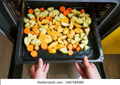 Vegetables - Zucchini, Potatoes And Carrots - Lie On A Baking Sheet Sprinkled With Spices. Hands Put A Baking Sheet In The Oven. The Concept Of Cooking Vegetarian Food, A Fresh Crop Of Vegetables.