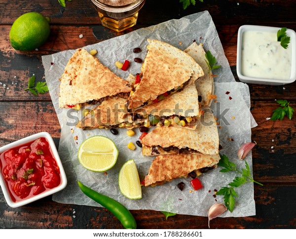 vegetarian\
black beans tomato corn quesadilla served with cold beer salsa and\
yogurt dip sause on dark wooden\
background