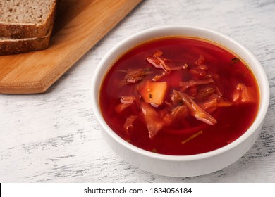 Vegetarian borscht in a white tureen on a light wooden table near pieces of bread. - Shutterstock ID 1834056184