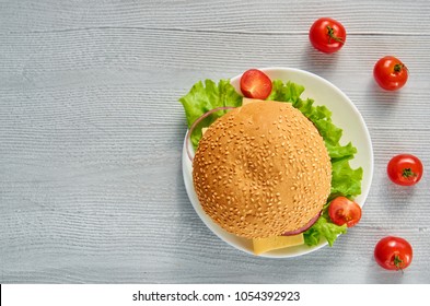 Vegetarian Burger Decorated With Fresh Cherry Tomatoes On The Gray Concrete Background With Free Copy Space. Classic American Veggie Burger. Top View