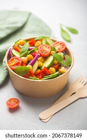 Vegetarian chickpea beans salad prepared with tomatoes, cucumber, red onion, cress salad and arugula in a paper bowl. Zero waste dishware such as wooden fork and paper bowl - Shutterstock ID 2067378149