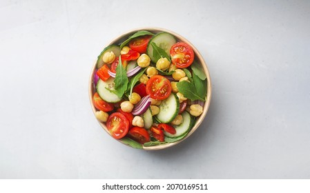 Vegetarian chickpea salad prepared with tomatoes, cucumber, red onion, cress salad and arugula in a paper bowl. Chickpeas are rich in protein and fiber. Zero waste dishware, top view - Shutterstock ID 2070169511