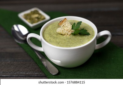 Vegetarian cream of broccoli, potato, onion, garlic, sesame and olive oil, and coconut milk soup. served in a white ceramic plate on a dark brown wooden board using green textile - Powered by Shutterstock