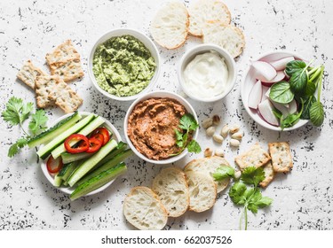 Vegetarian dip table. Eggplant, harissa, walnuts dip, broccoli dip, soft tofu and fresh vegetables on a light background, top view. Flat lay      - Powered by Shutterstock