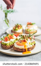 Vegetarian egg sandwiches on white background. Healthy vegetarian sandwiches with egg tomatoes avocado cream and cheese garnished with chia seeds and aromatic herbs. Vegetarian sandwich.