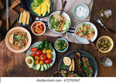 Vegetarian Food Concept. Set Of Healthy Vegetarian Food, Salad With Bulgur Porridge And Vegetables, Stuffed Eggplant, Vegetables, Mango, Avocado And Snacks On A Wooden Table, Top View