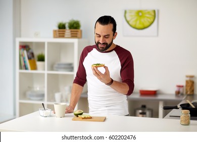 Vegetarian Food, Healthy Eating, People And Diet Concept - Man Having Avocado Sandwiches For Breakfast At Home Kitchen