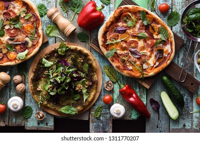 Vegetarian food with raw ingredients. Green pesto pizza, tomato and mushrooms pizza on shabby blue background top view