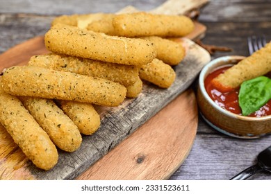 Vegetarian iitalian cheese breaded  oven baked  mozzarella sticks with  fresh basil on wooden background.Italian street food. - Powered by Shutterstock