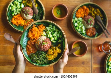 Vegetarian Indian Food. Dish With Rice, Ogricami, Spinach, Carrots And Sauce, On A Sheet Of Banana Tree In The Hands Of A Man.