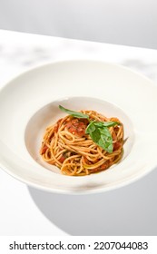 Vegetarian Pasta With Basil And Tomatoes On White Plate. Tomato Pasta In Summer Menu With Hard Shadows. Spaghetti With Tomatoes On Light Background. Vegan Food - Spaghetti Marinara