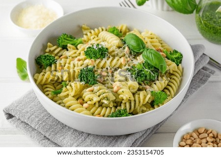 Vegetarian pasta with pesto sauce, broccoli, parmesan cheese and pine nuts on a white wooden background. Healthy food