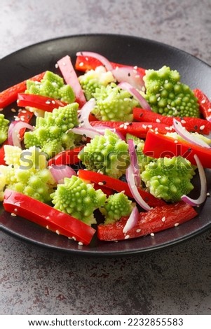 Vegetarian salad of steamed romanesco broccoli, bell pepper and red onion close-up in a plate on the table. Vertical