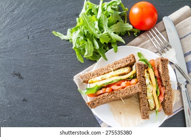 Vegetarian Sandwich With Zucchini Burger, Cheese, Ruccola And Tomatoes, White Plate, Dark Stone Background, Top View