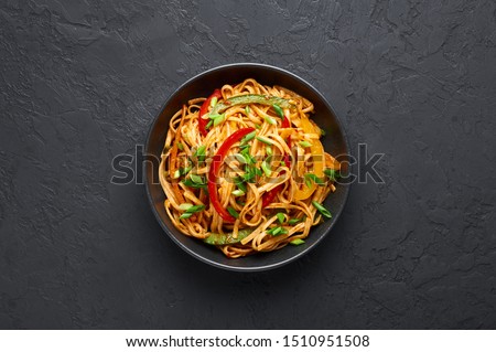 Vegetarian Schezwan Noodles or Vegetable Hakka Noodles or Chow Mein in black bowl at dark background. Schezwan Noodles is indo-chinese cuisine hot dish with udon noodles, vegetables and chilli sauce