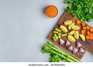 Vegetarian Set Of Raw Vegetables On Wooden Cutting Board On Light Background. Chopped Carrots, Potatoes, Red Onions, Lentsils, Parsley. Preparing Ingredients For Cooking Soup. Horizontal, Copy Space