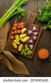 Vegetarian Set For Soup Of Raw Vegetables On Wooden Cutting Board. Chopped Carrots, Potatoes, Red Onions, Lentsils, Parsley. Preparing Ingredients For Cooking. Diced And Sliced Products. Vertical