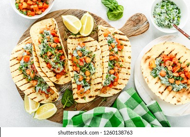 vegetarian snack of tacos with chickpea curry and sour cream sauce with parsley, spinach, green onions and sprouted flax seeds. healthy plant based food. top view on light background, flat lay