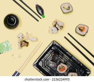 Vegetarian Sushi, Takeaway Concept. Many Chopsticks From Above With Plenty Of Pieces Of Rolled Sushi In Nori Dried Edible Seaweed With Rice Salmon, Squid, Carrots, Rice Cubes. Black Disposable Plate