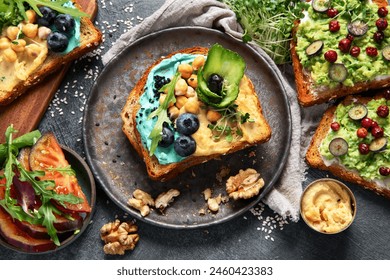 Vegetarian toasts with hummus, blueberry, avocado, tomato. delicious vegan breakfast on dark background. Top view