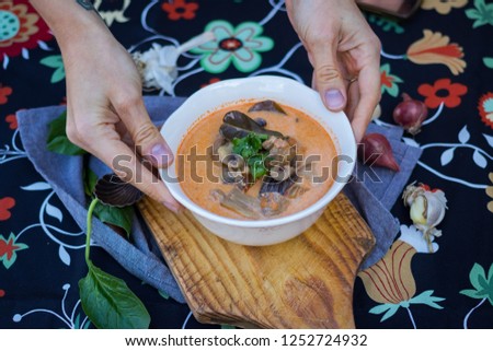 Vegetarian Tom Yum soup. Woman hands holds Asian hot sour Thai food with mushrooms broth and lemongrass leaves in bowl. Vegan healthy food.
