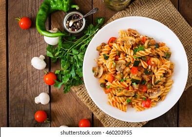 Vegetarian Vegetable pasta Fusilli  with zucchini, mushrooms and capers in white bowl on wooden table. Top view - Shutterstock ID 460203955