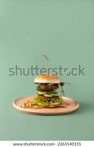 Veggie burger with lettuce and cucumber on green background