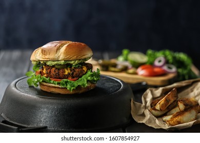 Veggie Burger On A Dark Background With Potato Veggies And Vegetables On The Background. Overhead Shot.