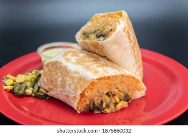 Veggie Burrito Loaded With Fresh Vegetables Cut In Half And Presented On A Red Plate.