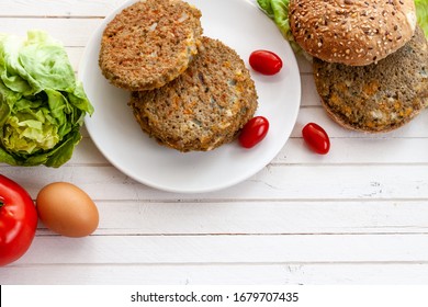 Veggie Quinoa Burger With  Tomato, Burger Bread, Onion, Lettuce On A White Dish, With Copy Space.