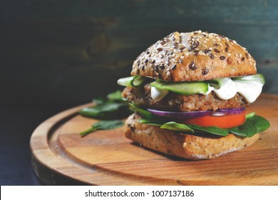 veggie, vegan burger with buckwheat, tomato, onion, vegan mayonnaise and spinach on a fresh bun with flax seeds and sesame, surrounded by spinach leaves - Shutterstock ID 1007137186