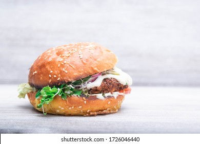 veggie, vegan burger tomato, onion, on a fresh bun with flax seeds and sesame. Vegan lentils burger with vegetables. Light background, copy space. Vegan food concept. - Powered by Shutterstock