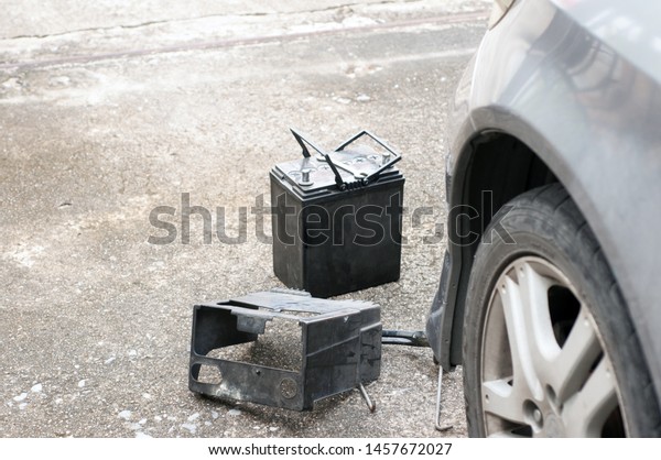 Vehicle car maintenance prearing to\
change the old battery with the new one, the damage battery with\
dusty case lay on in front of the car to change the\
new.