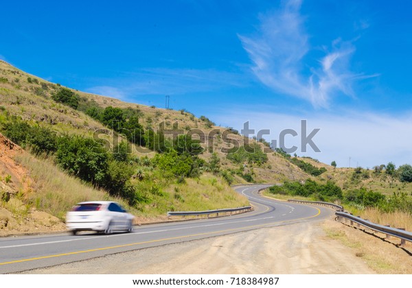 A vehicle at\
full speed on a curvy tarmac\
road