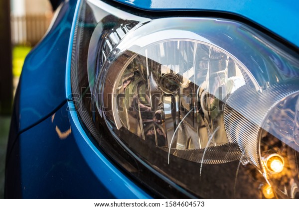 Vehicle headlight with\
the side light turned on.  Headlight surrounded by the metallic\
blue of the vehicle.