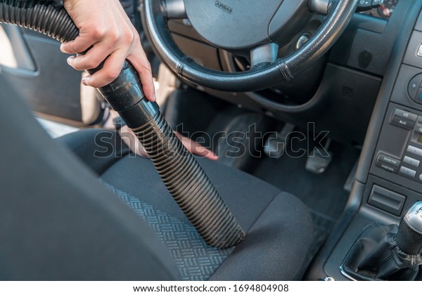 vehicle interior vacuum\
cleaning. Detail shot of an industrial vacuum cleaner cleaning a\
car seat