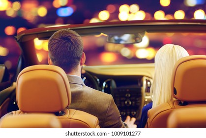 Vehicle, Luxury And People Concept - Close Up Of Couple Driving In Convertible Car Over Night City Lights Background