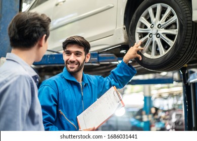 Vehicle Maintenance Handsome Man Servicer Explain Car Condition, Point At Vehicle Part To Asian Customer In Garage. Automotive Mechanic Hold Automotive Checklist Document. Car Repair Service Concept.