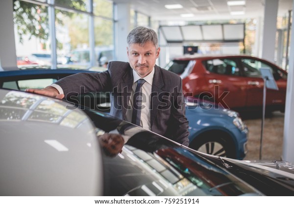 Vehicle manager in auto showroom. Dealer selling\
electro cars.