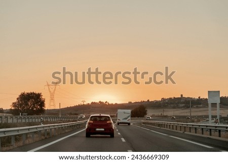 Vehicle on asphalt road, under sunset sky, driving on thoroughfare